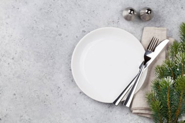 Taş zemin üzerine kar tarafından Noel tablo ayarını köknar ağacı dalı ile kaplı. Boş tabak, çatal ve bıçak. Selam yeri olan üstten görünüm