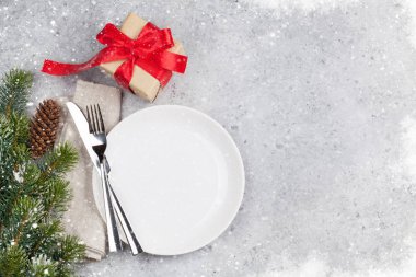 Taş zemin üzerine kar tarafından Noel tablo ayarını hediye kutusu ve köknar ağacı dalı ile kaplı. Boş tabak, çatal ve bıçak. Selam yeri olan üstten görünüm