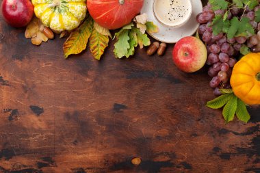 Sonbahar zemin kabak, elma, kahve, üzüm ve ahşap arka plan üzerinde renkli yaprakları ile. Metin alanı olan üstten görünüm