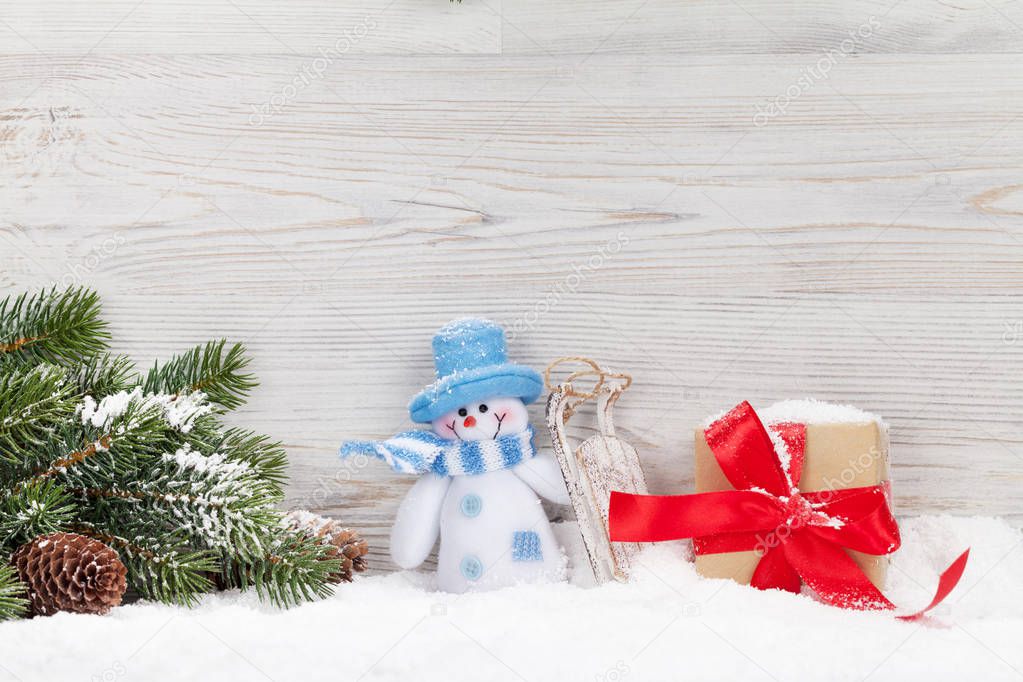 Christmas snowman toy, gift box and fir tree branch. Xmas greeting card with space for your greetings