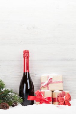 Noel hediye kutuları, şampanya şişesi ve xmas köknar ağacı dalı hafif ahşap zemin üzerine