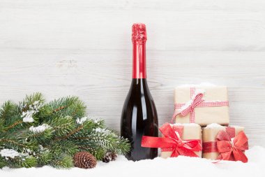Noel hediye kutuları, şampanya şişesi ve xmas köknar ağacı dalı hafif ahşap zemin üzerine