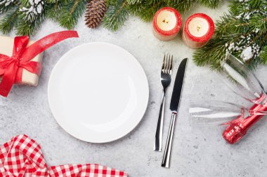 Taş zemin üzerine kar tarafından Noel tablo ayarını mumlar, şampanya, hediye kutusu ve köknar ağacı dalı ile kaplı. Selam yeri olan üstten görünüm