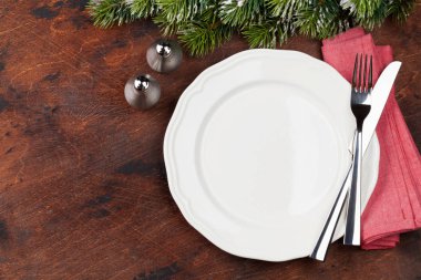 Ahşap arka plan üzerinde kar tarafından Noel tablo ayarını boş tabak, çatal bıçak ve köknar ağacı dalı ile kaplı. Selam yeri olan üstten görünüm