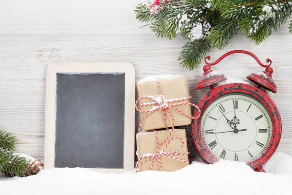 Weihnachtsgeschenkbox Wecker Und Schneebedeckter Tannenzweig Vor Der Holzwand Mit Kreidetafel — Stockfoto