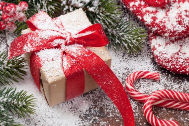 Ahşap masa üzerinde Noel kartı hediye kutusu, şekerler, sıcak eldiven ve xmas köknar ağacı dalları