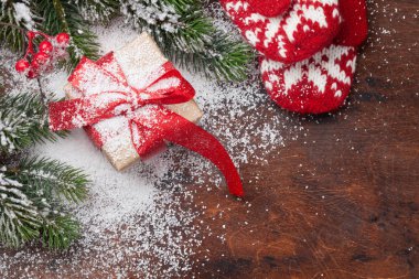 Ahşap masa üzerinde Noel kartı hediye kutusu, sıcak eldiven ve xmas köknar ağacı dalları