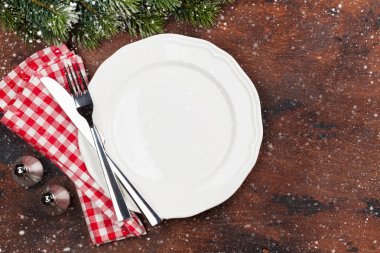 Ahşap arka plan üzerinde kar tarafından Noel tablo ayarını boş tabak, çatal bıçak ve köknar ağacı dalı ile kaplı. Selam yeri olan üstten görünüm