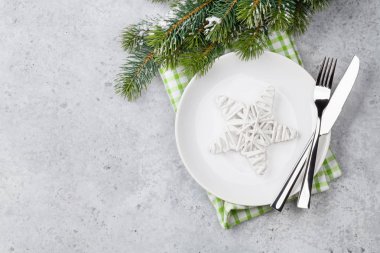 Noel tablo ayarı ile taş zemin üzerine tabak, çatal bıçak ve köknar ağacı dalı. Selam yeri olan üstten görünüm