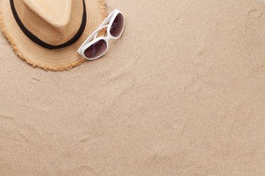Güneş gözlüğü ve kumlu plaj şapkası takarak seyahat etme kavramı. Kopyalama alanı olan üst görünüm. Düz yatıyordu
