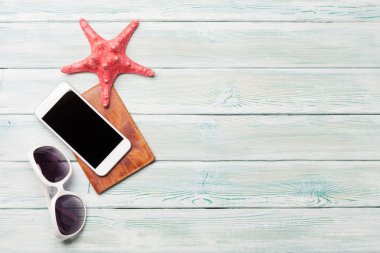 Tatil arka plan kavramı ile güneş gözlüğü, smartphone, pasaport ve denizyıldızı ahşap zemin üzerinde seyahat. Üstten görünüm kopya alanı ile. Düz yatıyordu