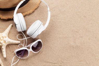 Seyahat tatili ve müzik konsepti. Kulaklık, güneş gözlüğü ve deniz yıldızıyla. Kopyalama alanı olan üst görünüm. Düz yatıyordu