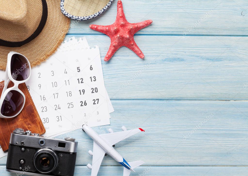 Travel vacation background concept with sunglasses, hat, camera, passport, airplane toy and calendar on wooden backdrop. Top view with copy space. Flat lay