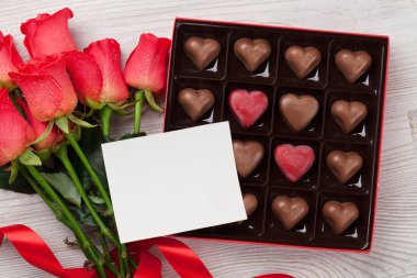 Sevgililer günü tebrik kartı kırmızı gül ve kalp şeklinde çikolata ahşap arka plan üzerinde. Tebrik için alan ile Üstten Görünüm