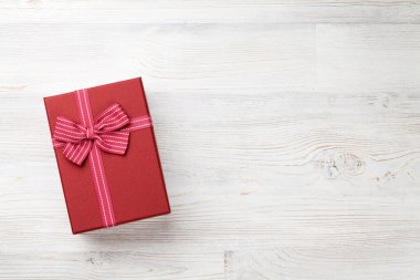 Ahşap masa üzerinde kırmızı hediye kutusu. Selam yeri olan üstten görünüm