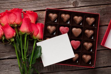 Kırmızı gül ve ahşap masa üzerinde çikolata kutusu Sevgililer günü. Metin alanı olan üstten görünüm