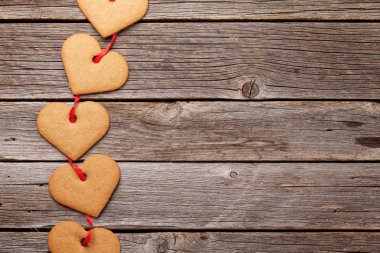 Sevgililer günü tebrik kartı kalp ile gingerbread çerezleri üzerinde ahşap arka plan şeklinde. Selam ile alan