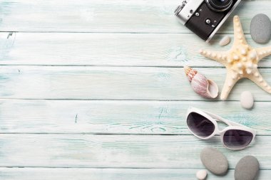Seyahat tatil arka plan kavramı ile fotoğraf makinesi, güneş gözlüğü ve kabukları ahşap masa üzerinde. Üstten görünüm kopya alanı ile. Düz yatıyordu