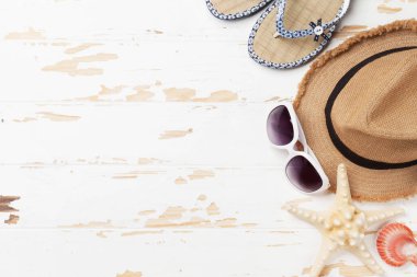 Tatil arka plan kavramı güneş şapkası, güneş gözlüğü, flip flop ve kabukları ile ahşap zemin üzerinde seyahat. Üstten görünüm kopya alanı ile. Düz yatıyordu