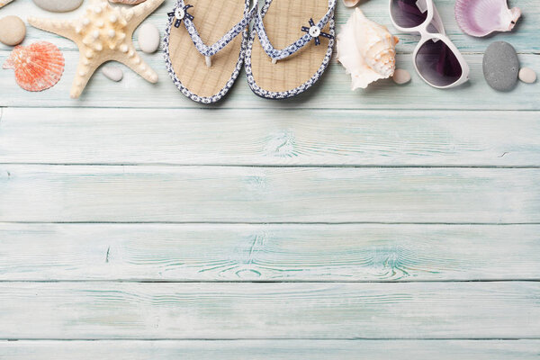 Travel vacation background concept with sunglasses, flip flops and seashells on wooden backdrop. Top view with copy space. Flat lay