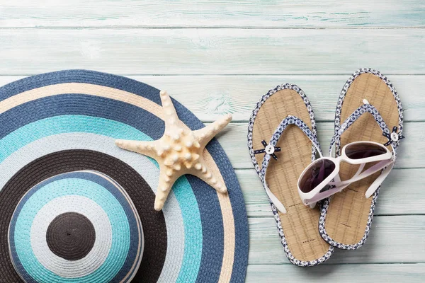 Travel vacation background concept with beach hat, sunglasses, flip flops and starfish on wooden backdrop. Top view with copy space. Flat lay