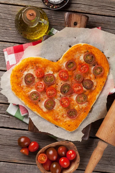 Heart shaped pizza with tomatoes and mozzarella. Valentines day greeting card. Top view