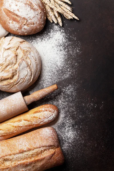 Various crusty bread and buns on stone table. Top view with space for your text