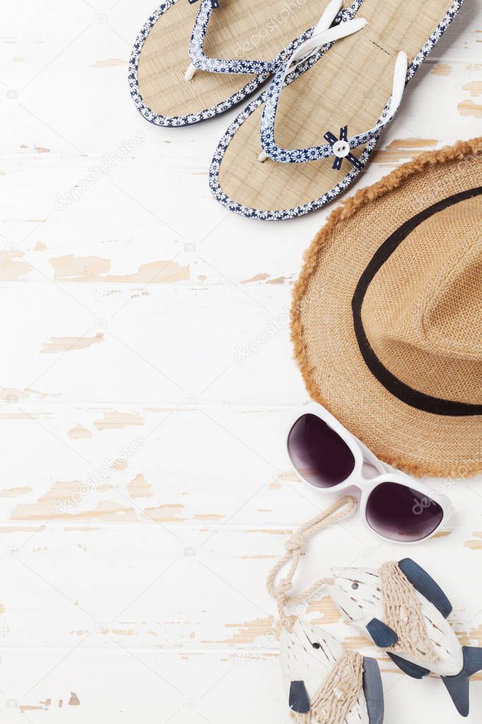 Travel vacation background concept with sun hat, sunglasses, flip flops and fish decor on wooden backdrop. Top view with copy space. Flat lay