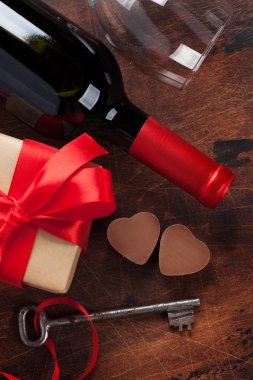 Sevgililer günü tebrik kartı ahşap arka plan üzerinde şarap şişesi, çikolata kalpleri ve hediye kutulu. Üstten görünüm