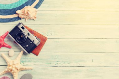 Seyahat tatil arka plan kavramı ile fotoğraf makinesi, pasaport ve kabukları ahşap masa üzerinde. Üstten görünüm kopya alanı ile. Düz yatıyordu. Sunny tonda