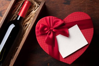 Sevgililer günü tebrik kartı ile kırmızı şarap şişe ve sevgi hediye kutusu ahşap arka plan üzerinde