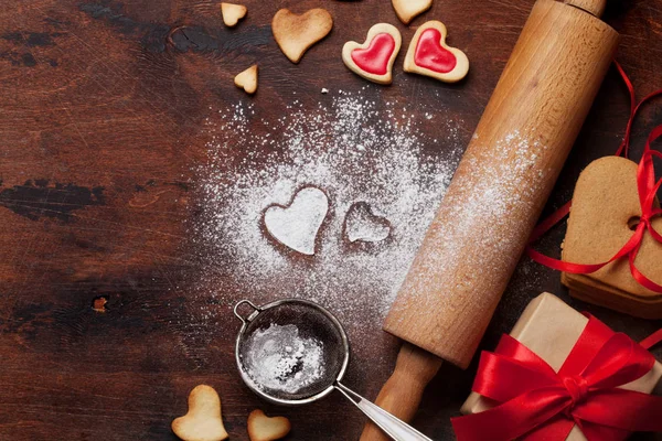 Valentine's day greeting card with cooking heart shaped cookies on wooden background