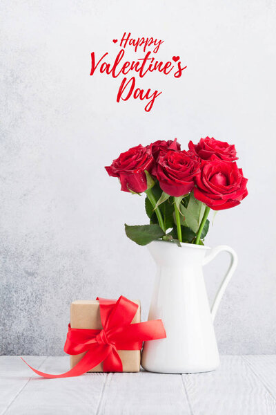 Открытки на день Святого Валентина с букетом из красных роз и подарочной коробкой перед каменной стеной
