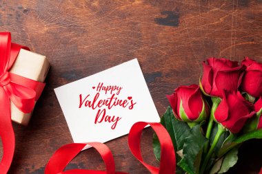 Sevgililer günü tebrik kartı ahşap arka plan üzerinde kırmızı gül çiçekler buket ve hediye kutulu. Selam yeri olan Üstten Görünüm