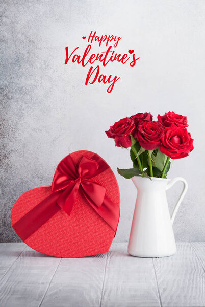 Открытки на день Святого Валентина с букетом из красных роз и подарочной коробкой на сердце перед каменным валом
