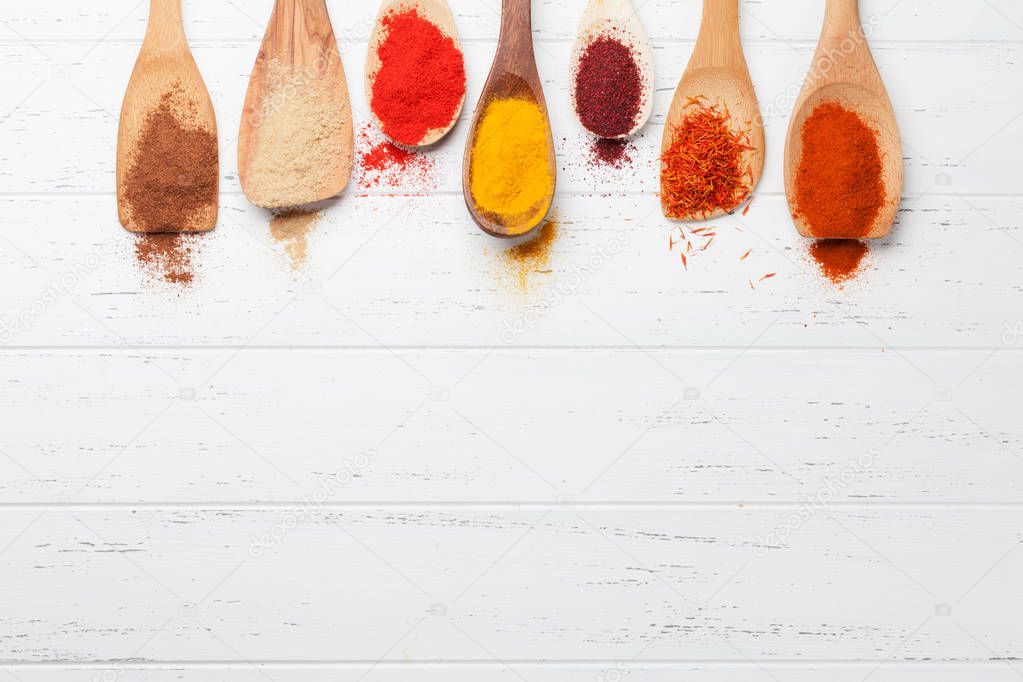 Set of various spices in spoons on wooden background. Top view with space for your recipe. Flat lay