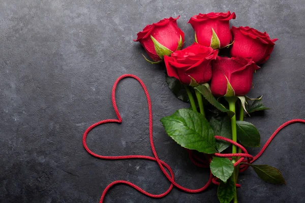 情人节贺卡与红玫瑰花花束和心脏形状在石头背景 — 图库照片