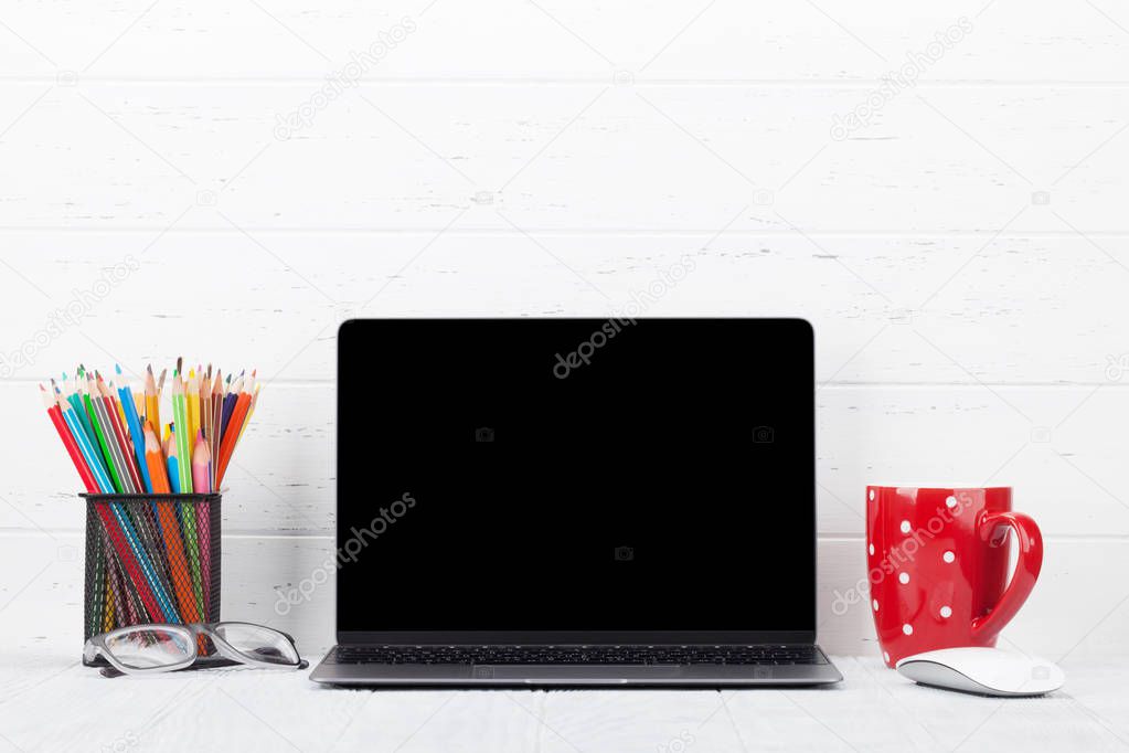 Loft home office workplace with blank black screen laptop computer, coffee cup and accessories. With copy space for your mockup or text