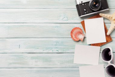Seyahat tatil kavramı ile güneş gözlüğü, fotoğraf makinesi ve fotoğraf çerçeveleri ahşap zemin üzerinde. Üstten görünüm kopya alanı ile. Düz yatıyordu