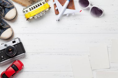 Tatil arka plan kavramı şapka, kamera, pasaport, Araba, tramvay, uçak oyuncak ve fotoğraf çerçeveleri ile ahşap zemin üzerinde seyahat. Üstten görünüm kopya alanı ile. Düz yatıyordu