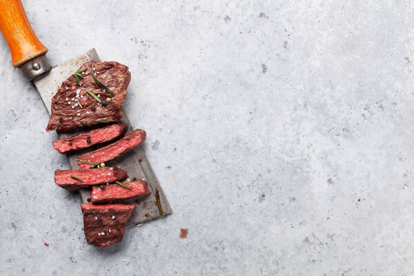 Top blade or denver grilled steak over meat butcher knife. Top view with copy space