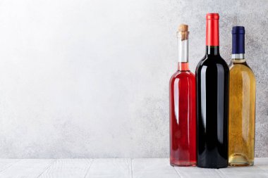 Kırmızı, gül ve beyaz şarap şişeleri taş duvar önünde. Senin metin için ile yer