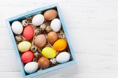 Beyaz ahşap masa kutusunda renkli yumurtalı Paskalya tebrik kartı. Selam yeri olan Üstten Görünüm