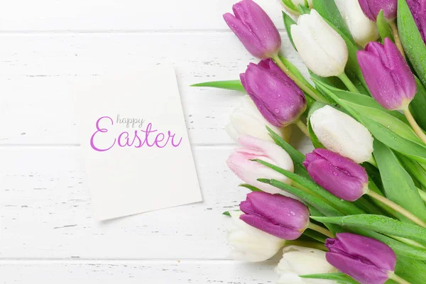 Easter greeting card with tulip flowers bouquet. Over white wooden table with space for your greetings