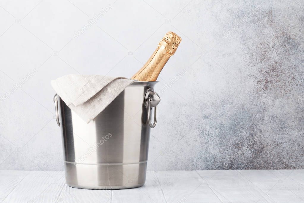 Champagne bottle in bucket in front of stone wall. With space for your text