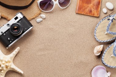 Tatil arka plan kavramı ile güneş gözlüğü, şapka, pasaport, fotoğraf makinesi ve denizyıldızı kum zemin üzerinde seyahat. Üstten görünüm kopya alanı ile. Düz yatıyordu