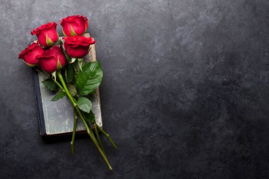 Sevgililer günü tebrik kartı ile kırmızı gül çiçekler buket üzerinde taş zemin üzerine eski kitap. Selam yeri olan Üstten Görünüm