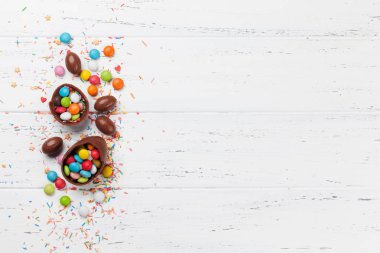 Çikolata yumurta ve şeker ile Paskalya tebrik kartı. Selam yeri olan ahşap masa üzerinde Üstten Görünüm