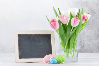 Lale çiçek ve Paskalya yumurta Paskalya tebrik kartı. Selam için kara tahta ile taş duvarın önünde