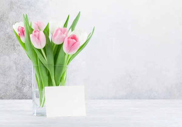 白の木製テーブルの上のカラフルなチューリップの花とイースターのグリーティング カード あなたの挨拶のためのスペースと — ストック写真